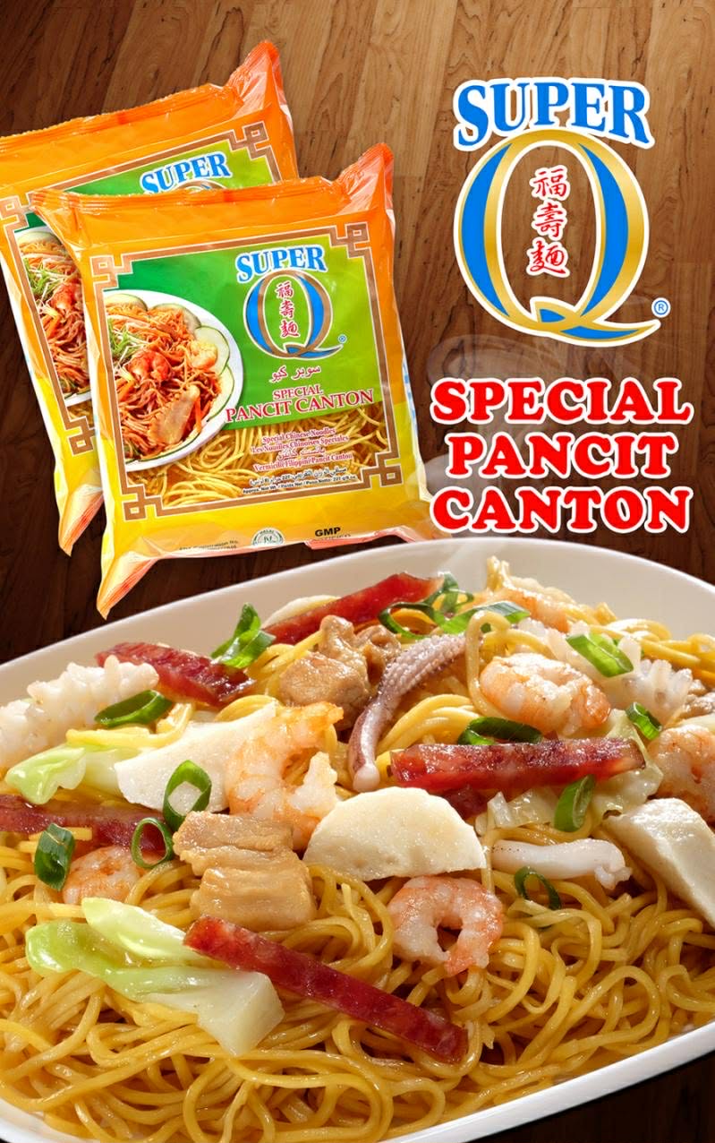 Two packs of Super Q Special Pancit Canton beside a plate of pancit canton with shrimp, squid, pork, Chinese sausage and cabbage